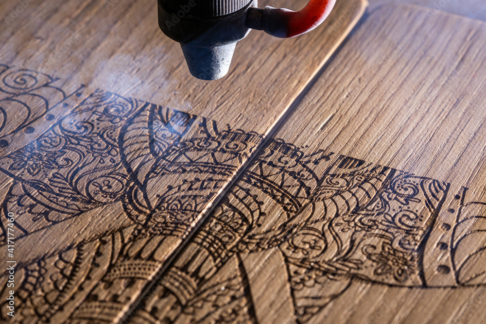 laser engraves the image of an Indian elephant on a wooden surface